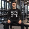 Build an Engine Not a Physique Long Sleeve Gym Shirt Seated model wearing a black long sleeve gym shirt with white “Built an Engine Not a Physique” lettering and a barbell graphic.
